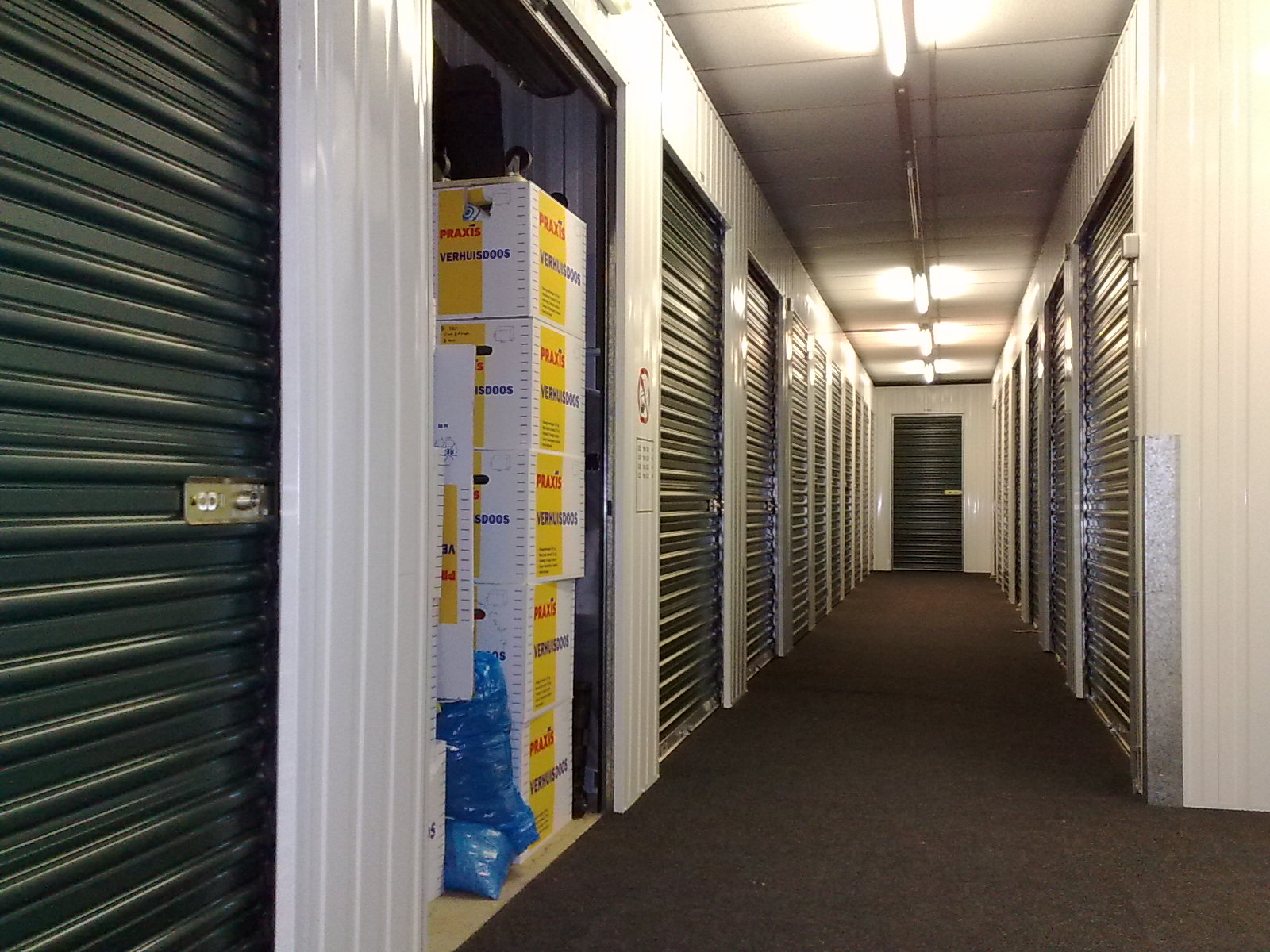 A clean indoor hallway of self storage units with roll-up doors